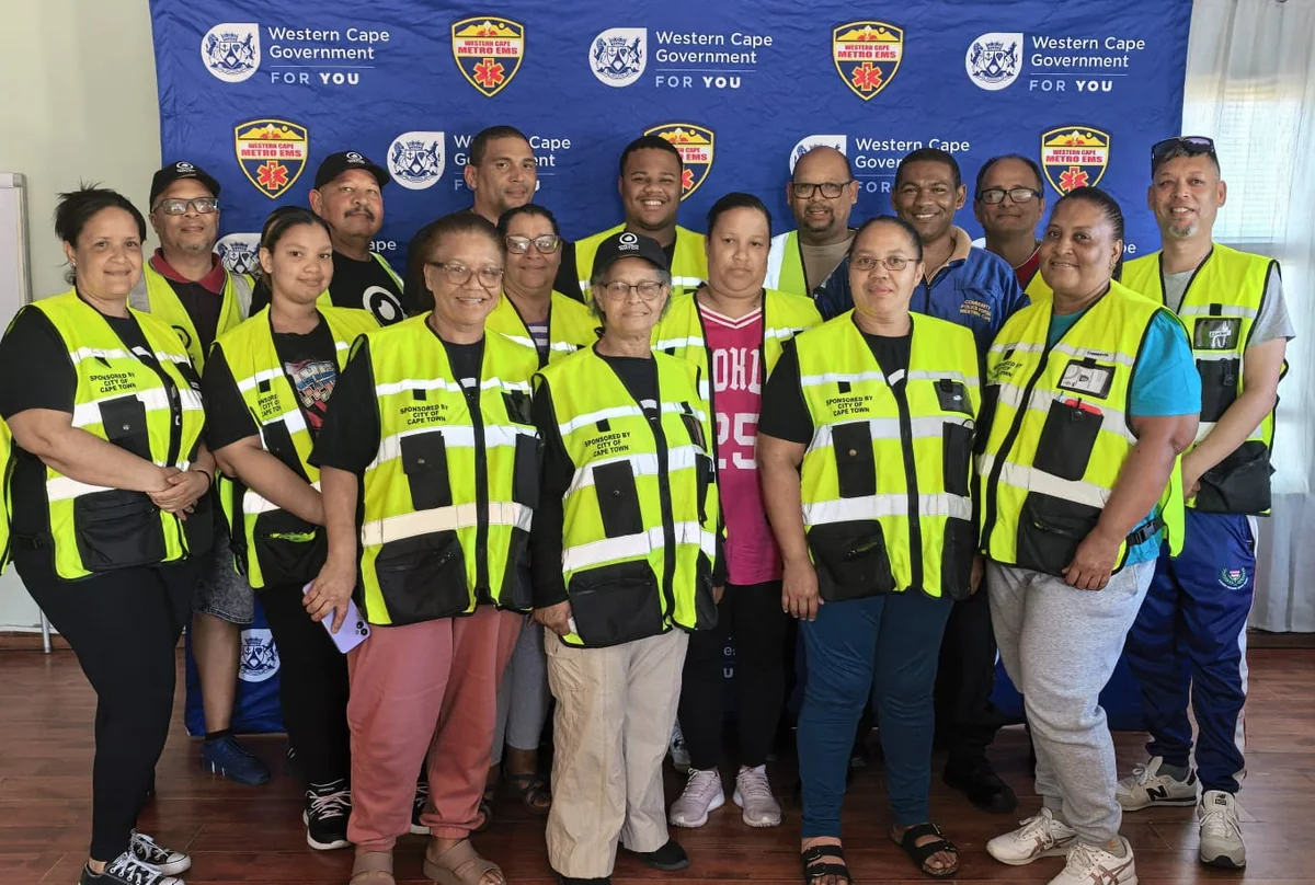 A neighbourhood-watch group assembled indoors in high-visibility vests in front of organisational branding.