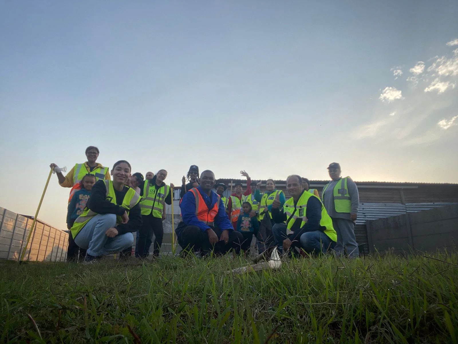 A Greenfields neighbourhood-watch group gathered outdoors in high-visibility clothing beneath an open sky.
