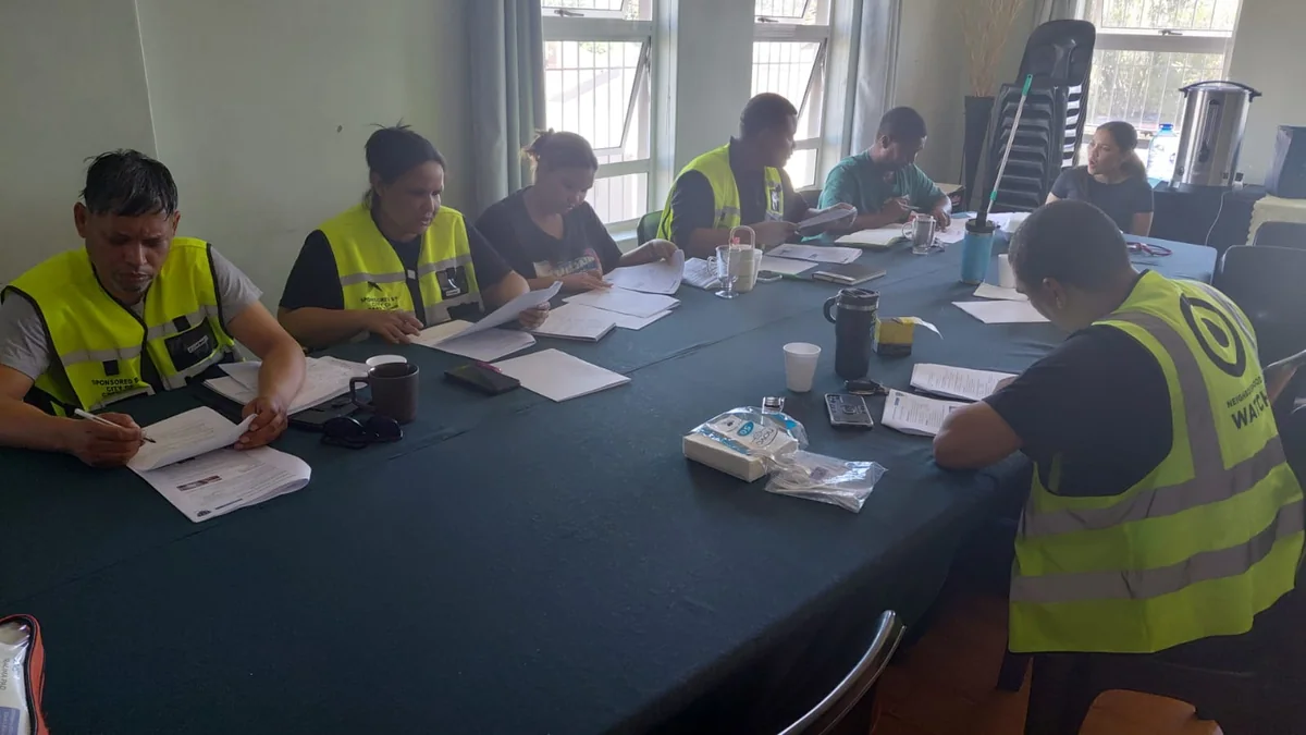 Neighbourhood-watch participants working around a table with printed materials during an indoor session.